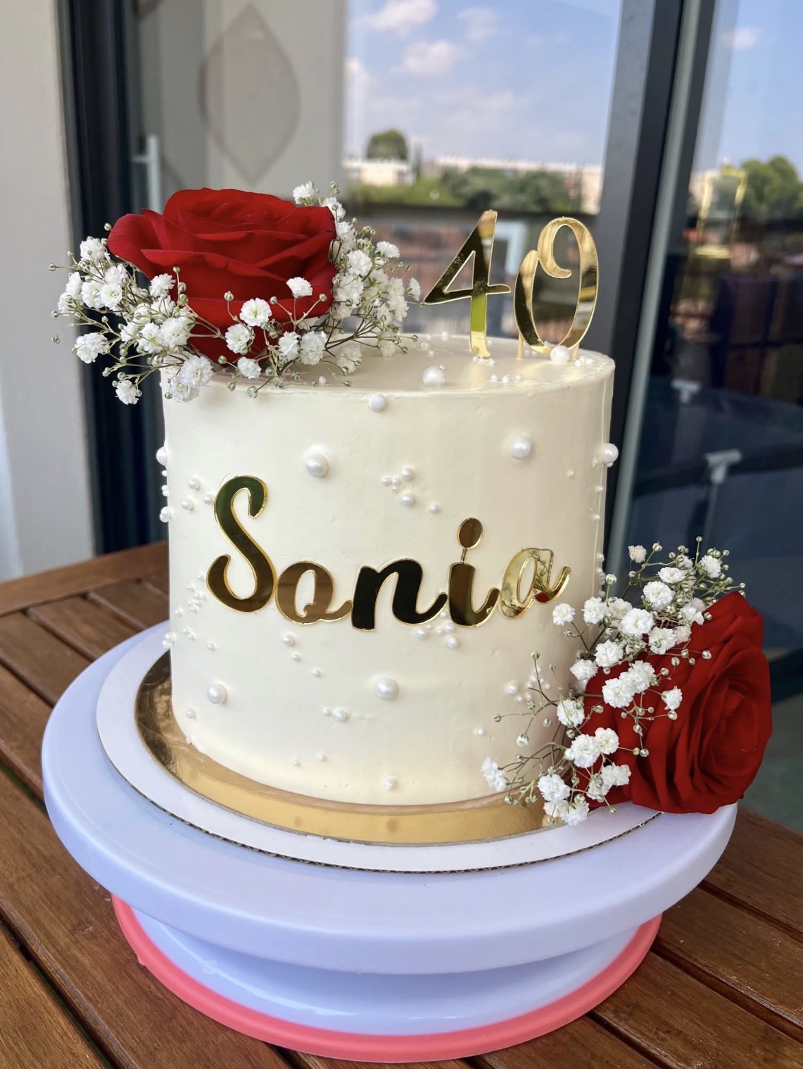 Gâteau d'anniversaire blanc, perles et roses rouges